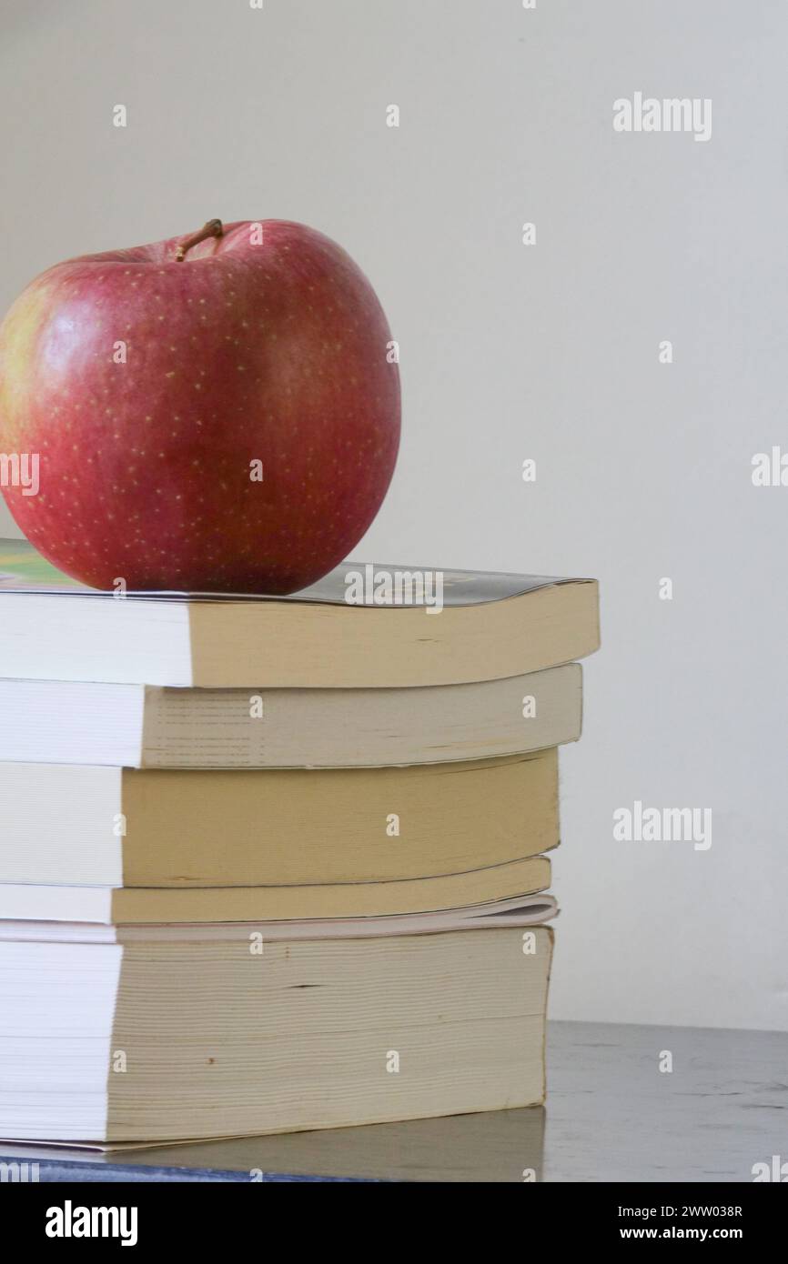 Una sola mela poggia su una pila di libri Foto Stock