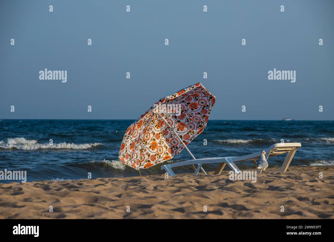 Ombrelloni lettini nuvole di spiaggia mare turchese. Ombrelloni colorati Panorama luce del sole di sabbia bianca. Foto Stock