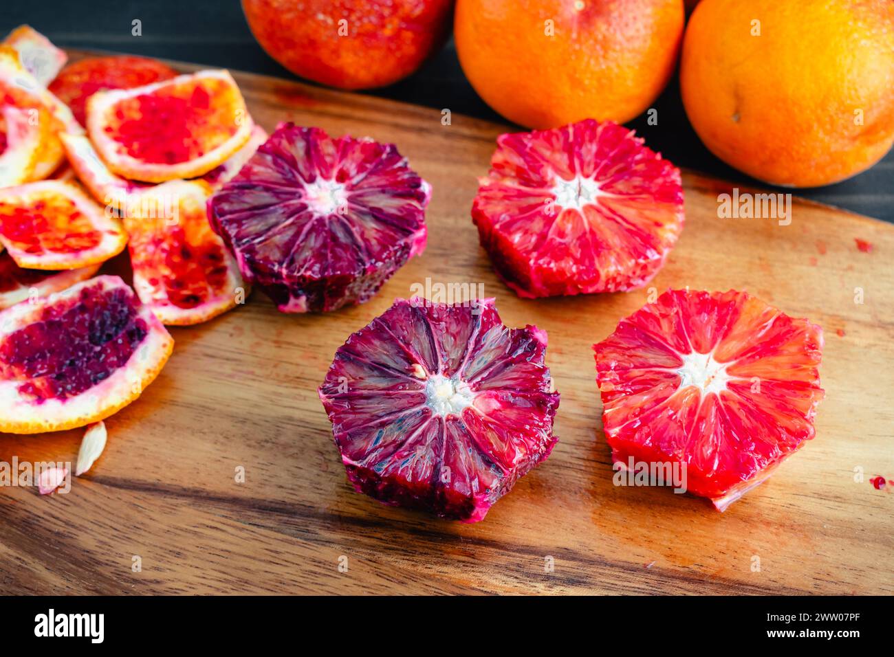 Arance di sangue sbucciate e deseminate su un tagliere di legno: Arance di lampone sbucciate, tagliate a metà e intere con bucce sul lato visto dall'alto Foto Stock