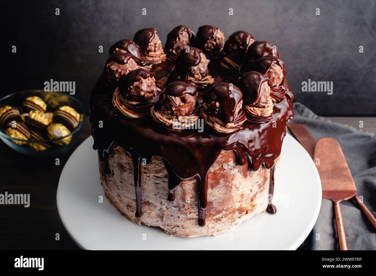 Torta al cioccolato alle nocciole con ganache al cioccolato e caramelle alle nocciole: Torta a strati di cioccolato con glassa di crema alle nocciole effetto acquerello Foto Stock
