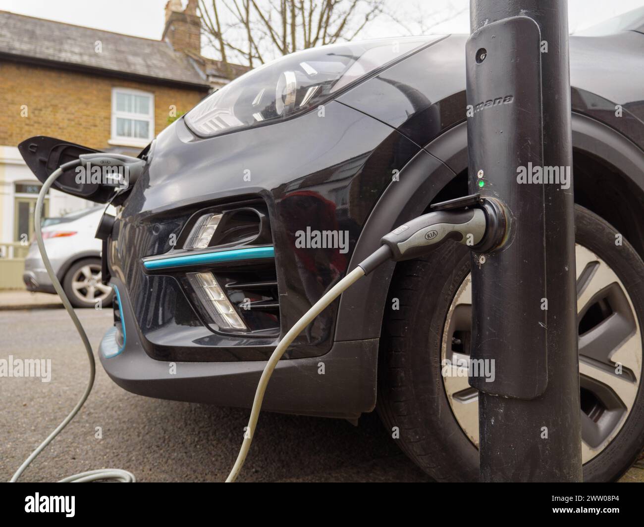 Auto elettrica collegata a un lampione di ricarica per veicoli elettrici in strada, Londra, Regno Unito Foto Stock