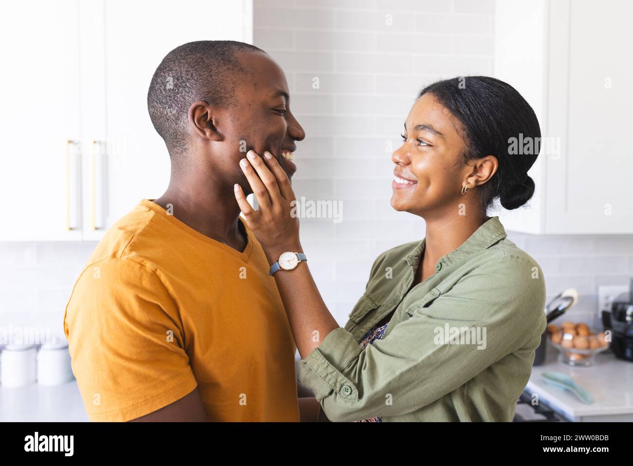 La coppia afroamericana condivide un momento tenero in cucina a casa Foto Stock