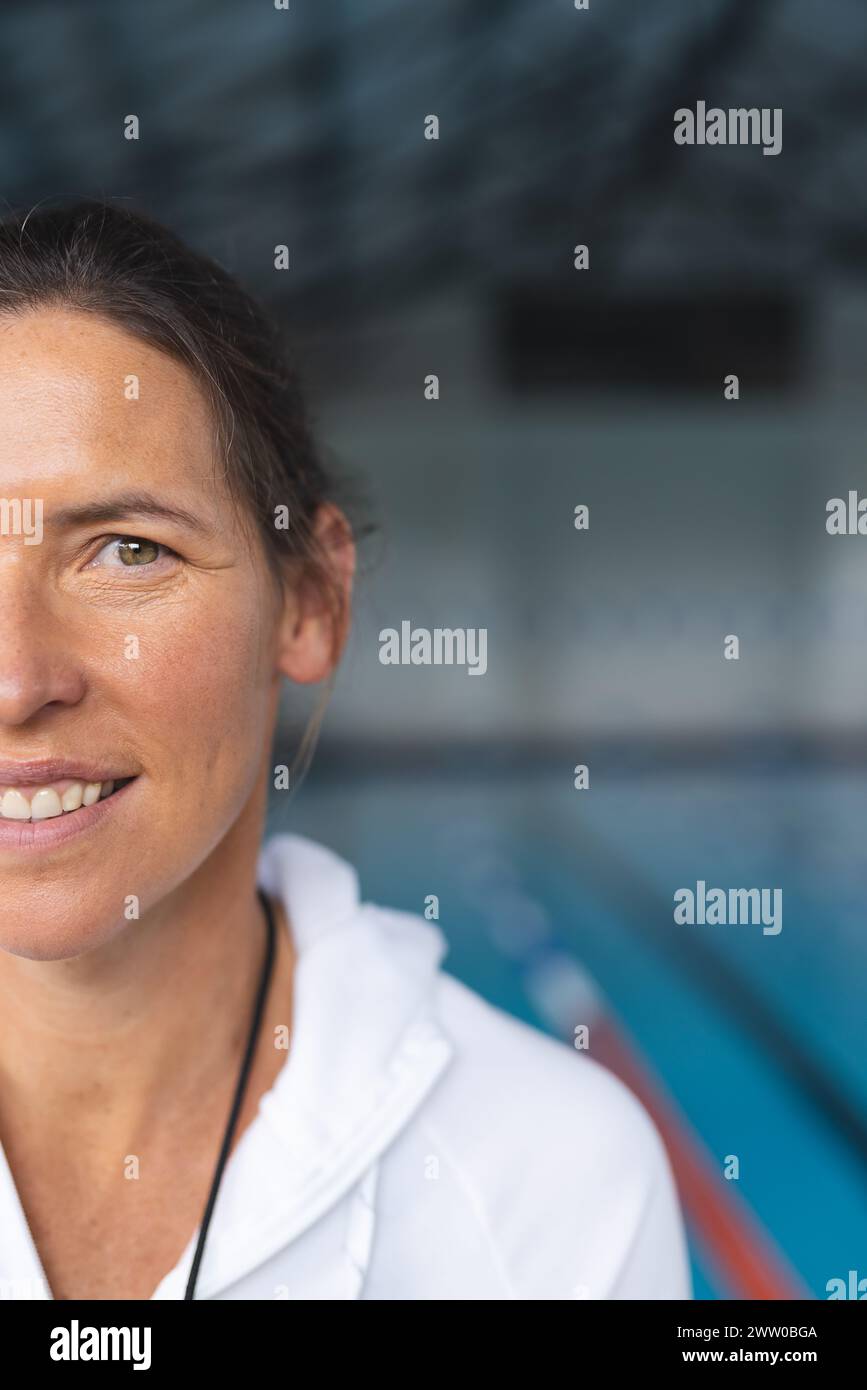 Una donna caucasica di mezza età si erge davanti a una piscina, sfondo blu con spazio per le copie Foto Stock