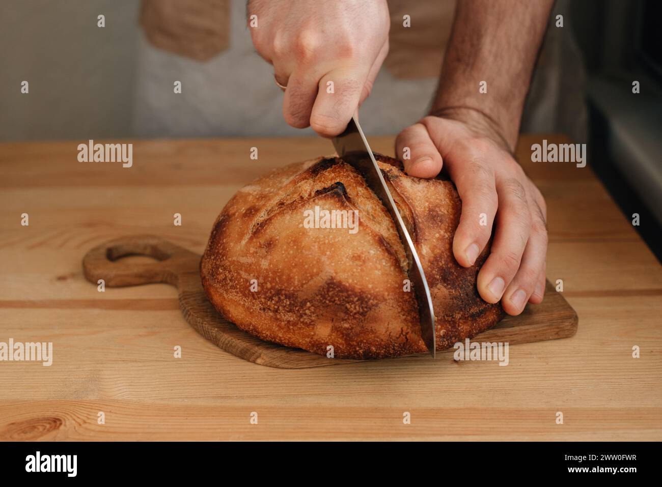 l'uomo affetta del pane fresco su un tavolo di legno. Foto di alta qualità Foto Stock