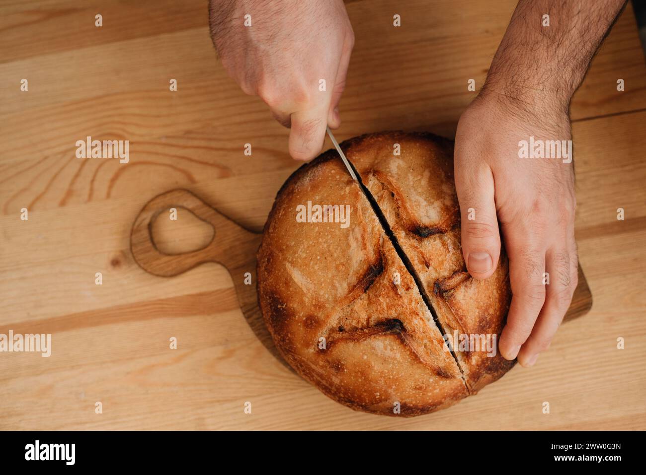 l'uomo affetta del pane fresco su un tavolo di legno Foto Stock