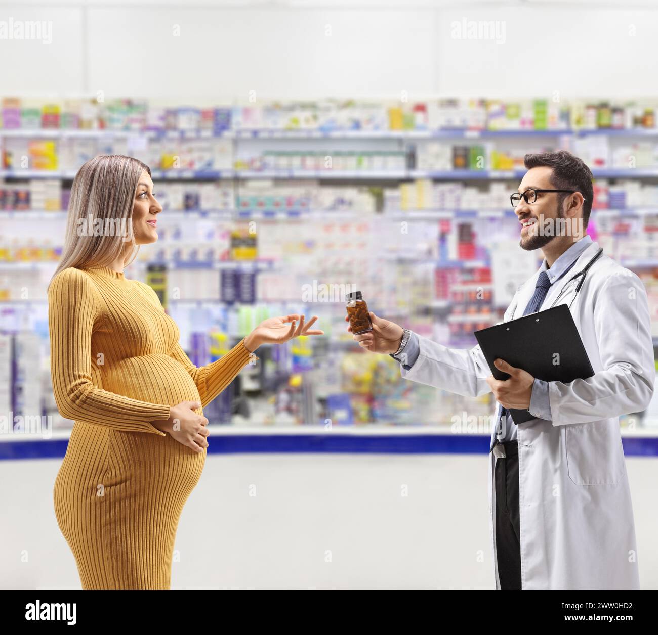 Medico che dà medicinali a una donna incinta all'interno di una farmacia Foto Stock