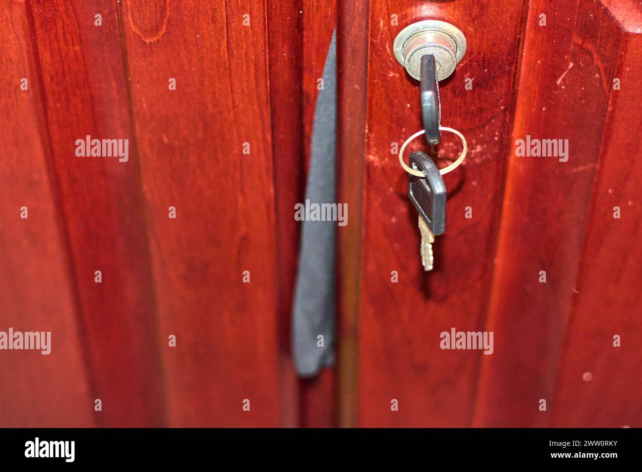 Immagine di una chiave inserita nella serratura di un armadietto di legno, che rappresenta la sicurezza e la privacy e un pezzo di abbigliamento che esce Foto Stock