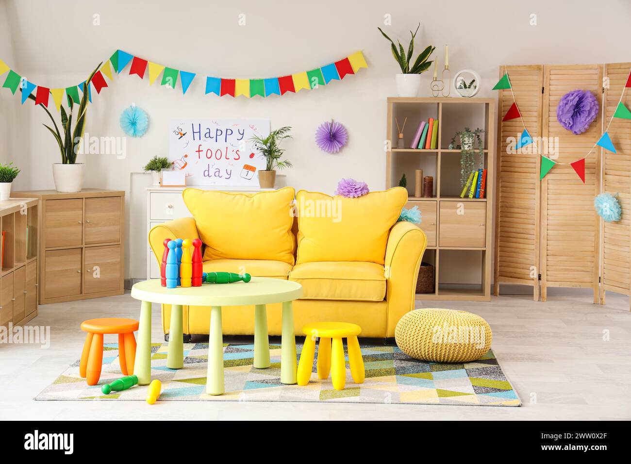 Interno del soggiorno decorato per il giorno del Fool di aprile con divano e giocoleria sul tavolo Foto Stock