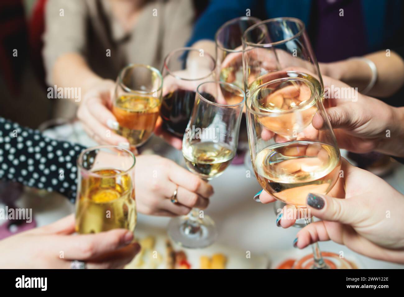 Il gruppo di ospiti festeggia e solleva i bicchieri, brinda e applaude con bicchieri alcolici con vino e champagne nel ristorante del battesimo aziendale Foto Stock