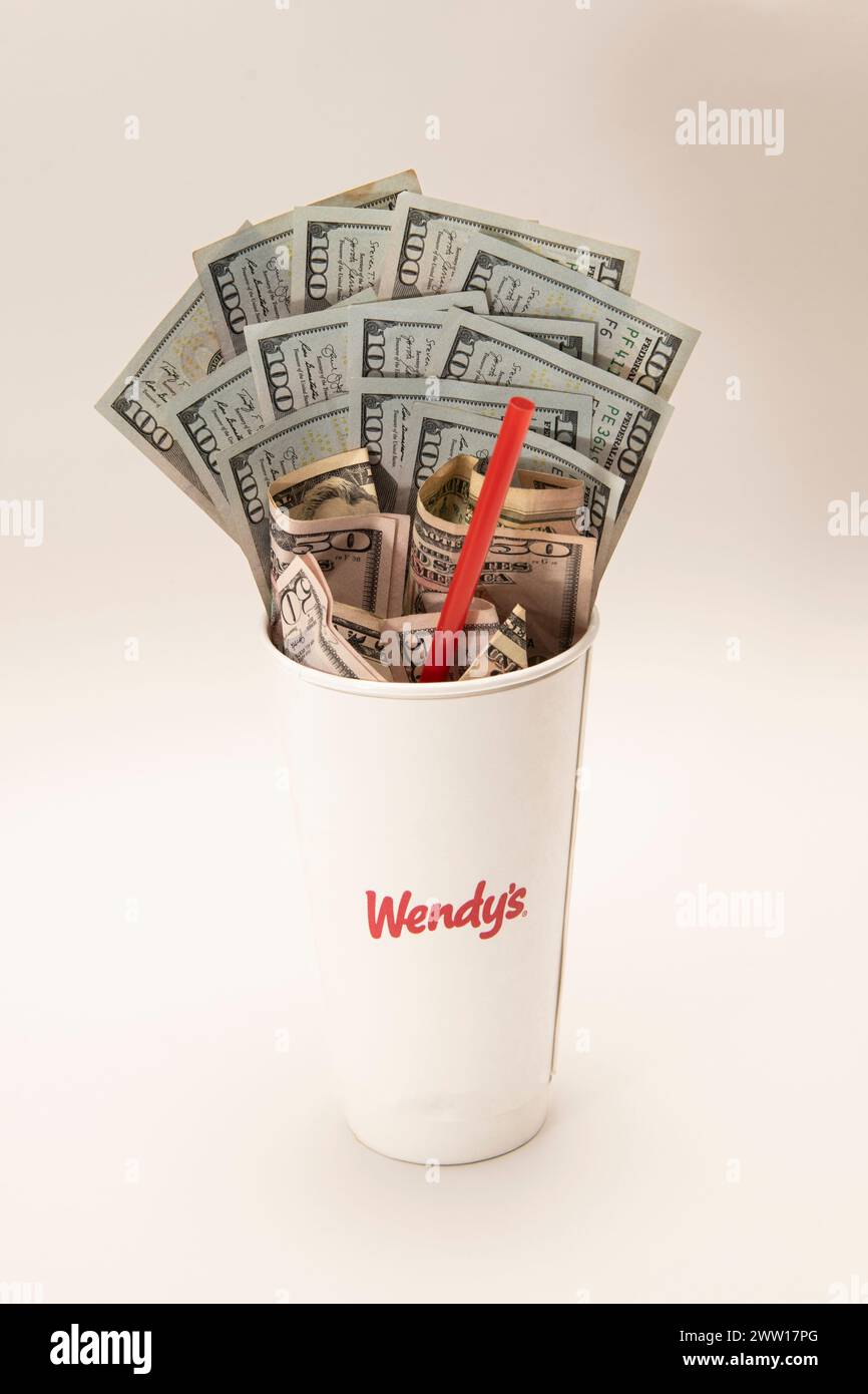 Maplewood, Minnesota. Wendy e' catena di fast food. La tazza di bibita di Wendy è piena di soldi e una cannuccia su sfondo bianco. Foto Stock