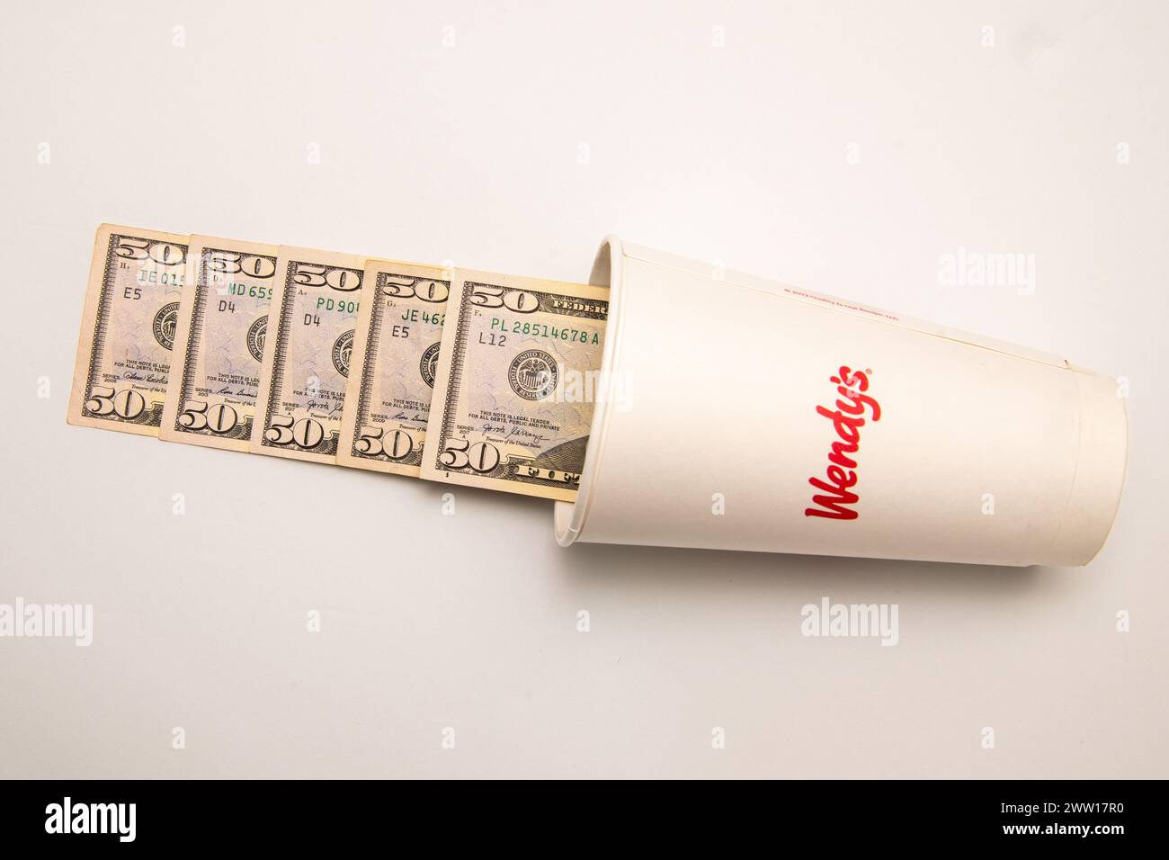 Maplewood, Minnesota. Wendy e' catena di fast food. La tazza di bibita di Wendy con i soldi che fuoriescono dalla tazza su sfondo bianco. Foto Stock