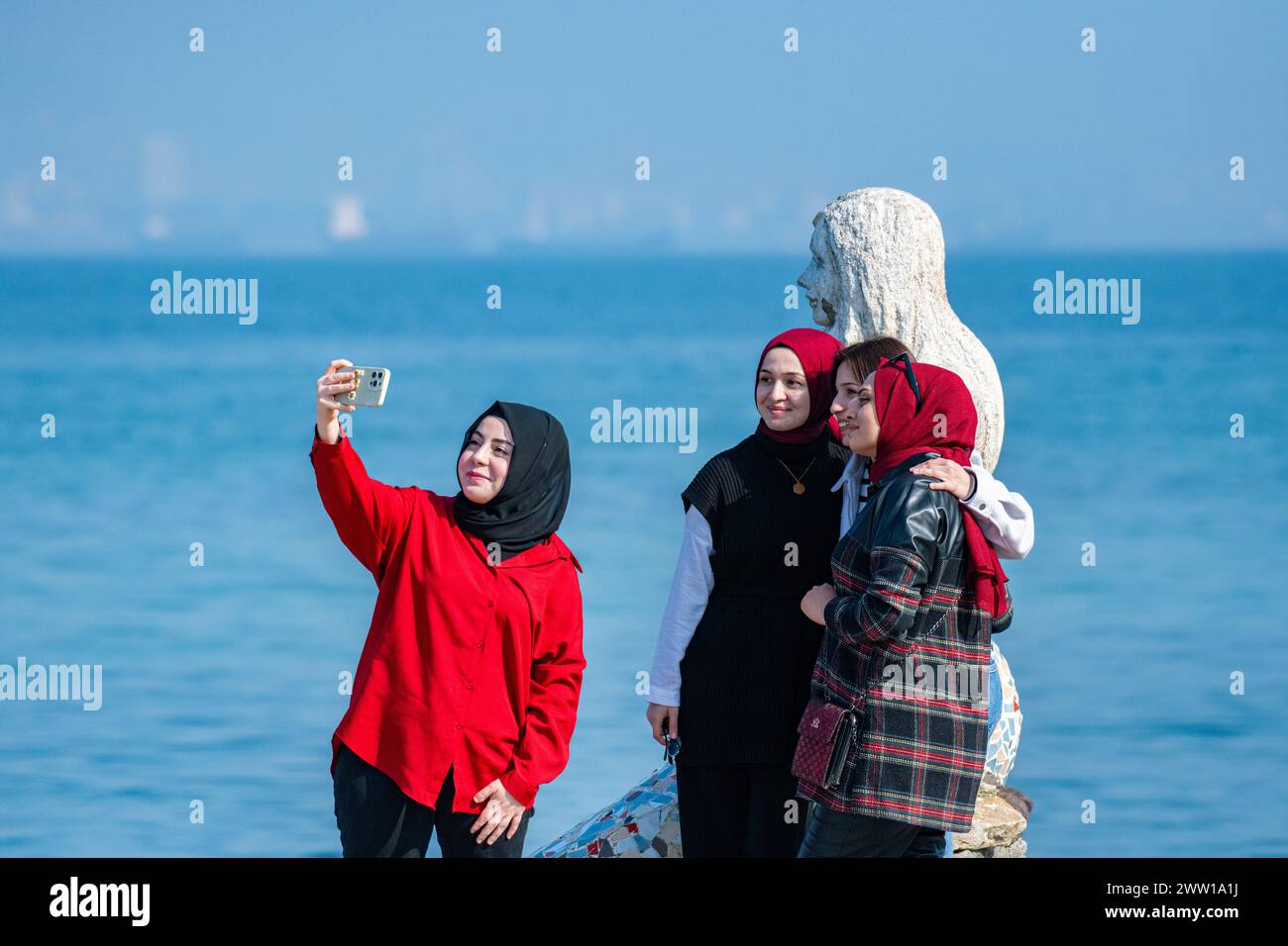 Le ragazze musulmane invidiano il sole con un selfie con una statua di una sirena sull'Isola dei principi, un arcipelago vicino al centro di Istanbul in Turchia Foto Stock