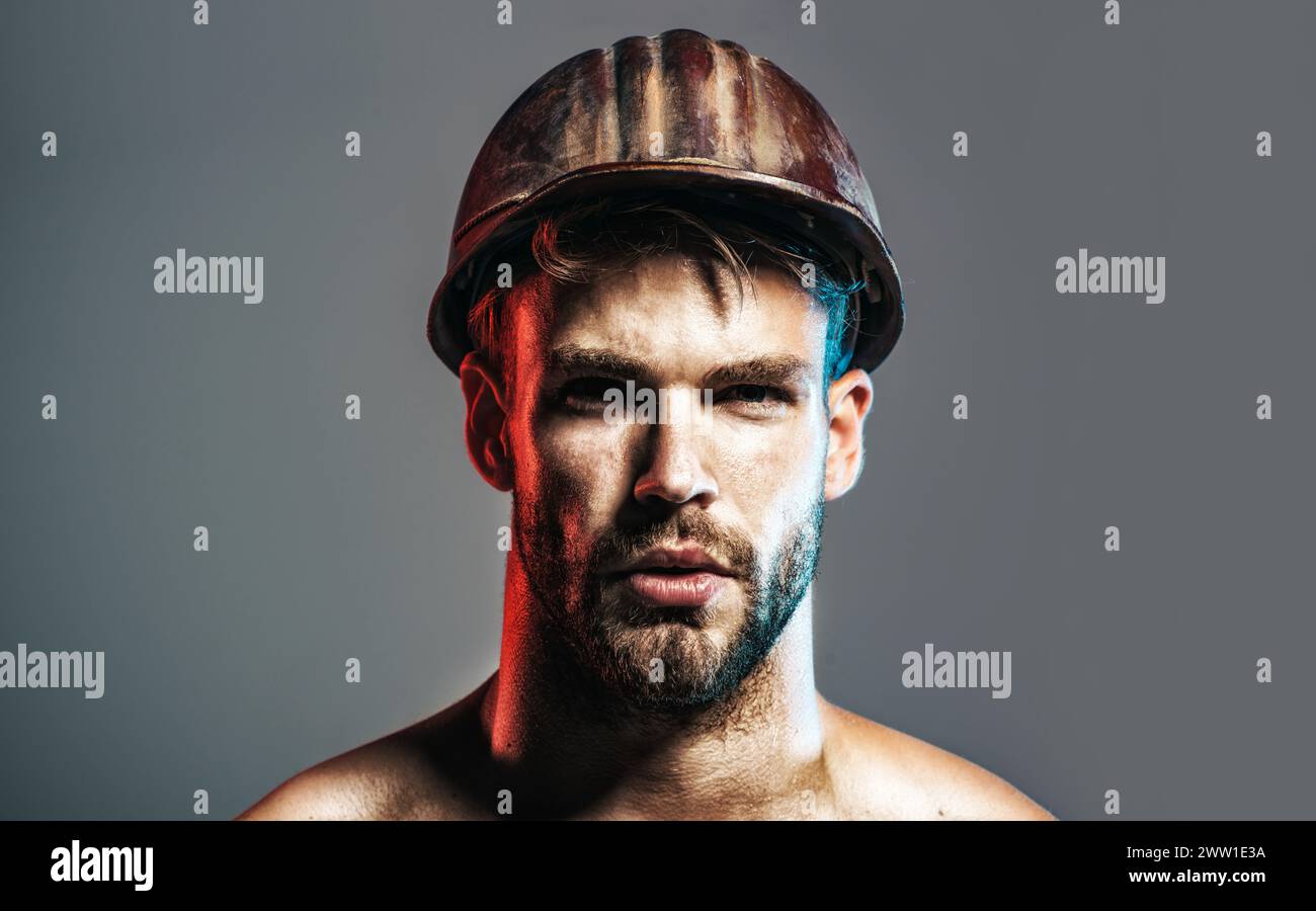 Primo piano ritratto costruttore serio con casco protettivo. Bell'ingegnere, architetto o lavoratore industriale maschile in elmetto di sicurezza. Forte barba Foto Stock