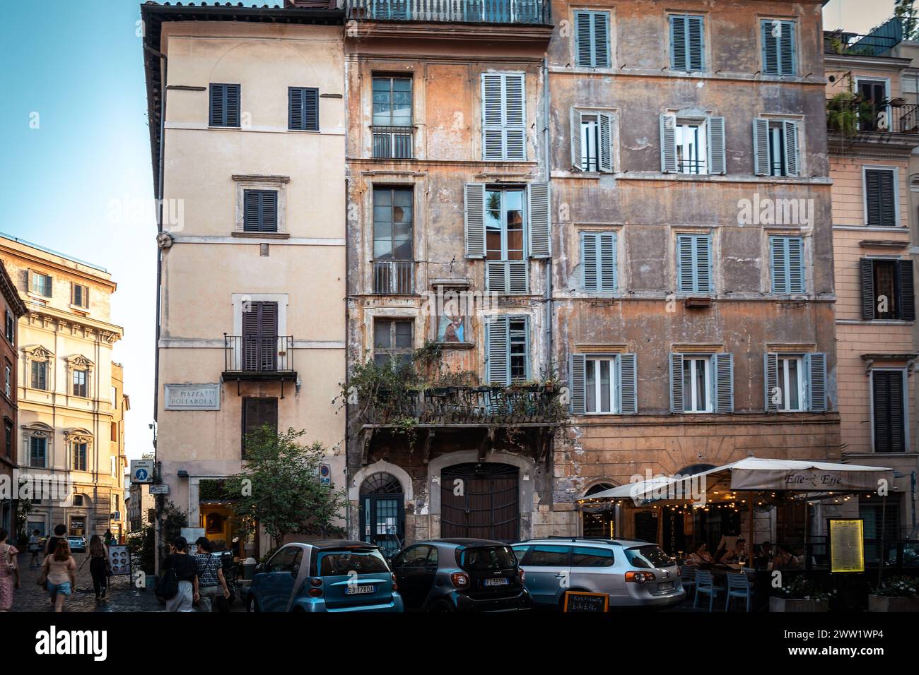 Roma, Italia - 14 agosto 2023: Auto moderne parcheggiate di fronte a un vecchio condominio fatiscente Foto Stock