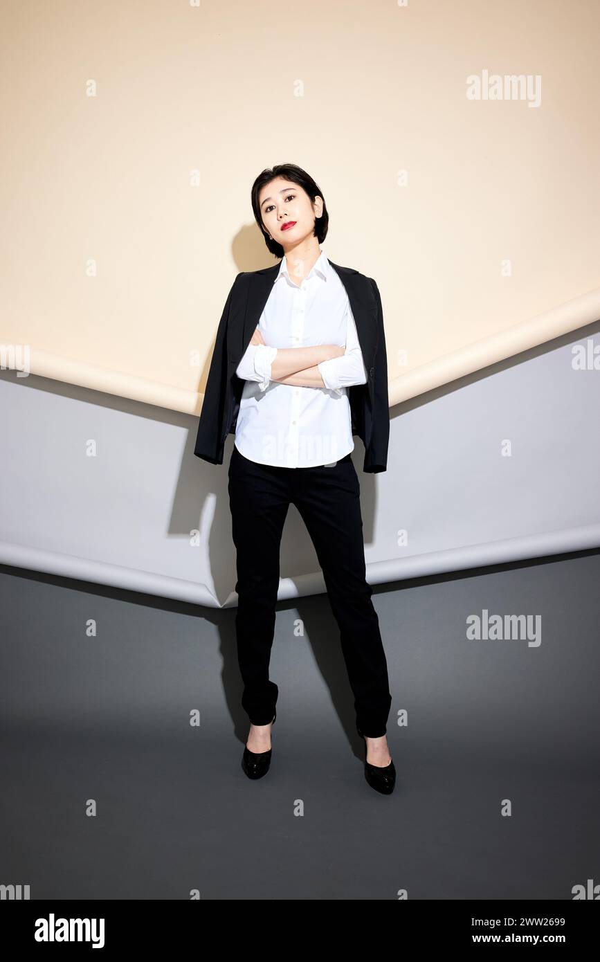 Una donna con pantaloni neri e una camicia bianca Foto Stock