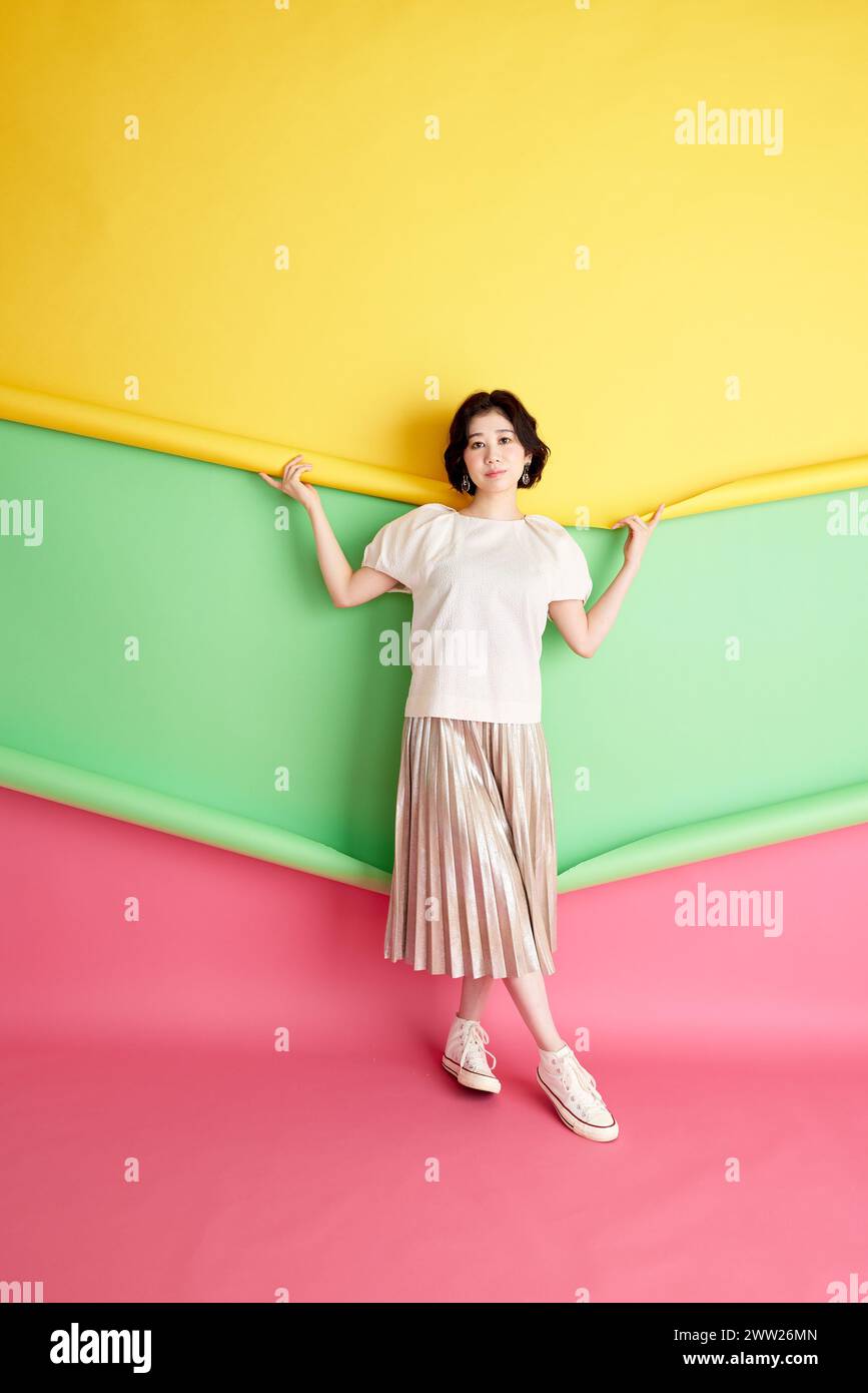 Una donna in piedi davanti a un muro colorato Foto Stock