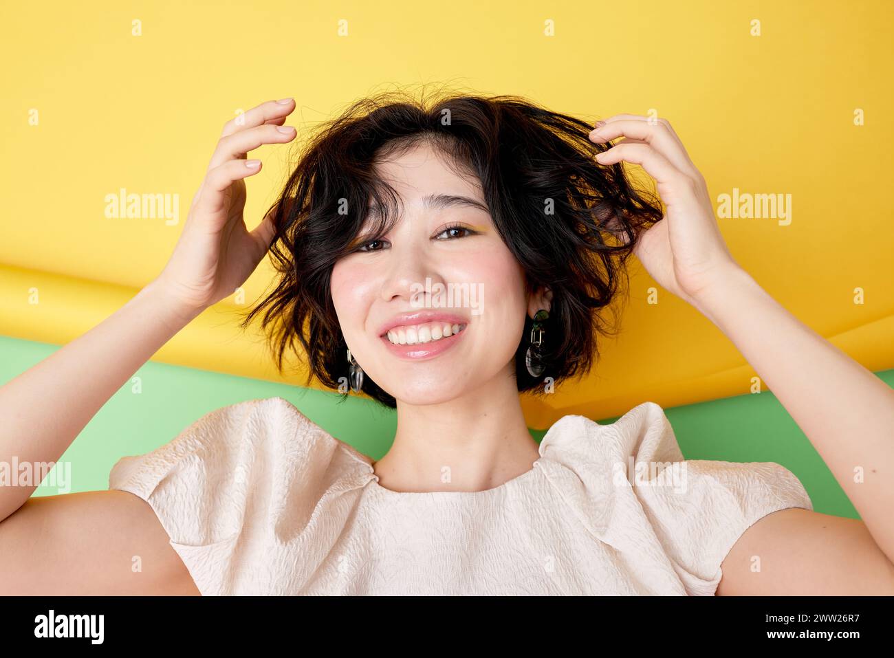Una donna con i capelli corti che sorride e tiene i capelli Foto Stock