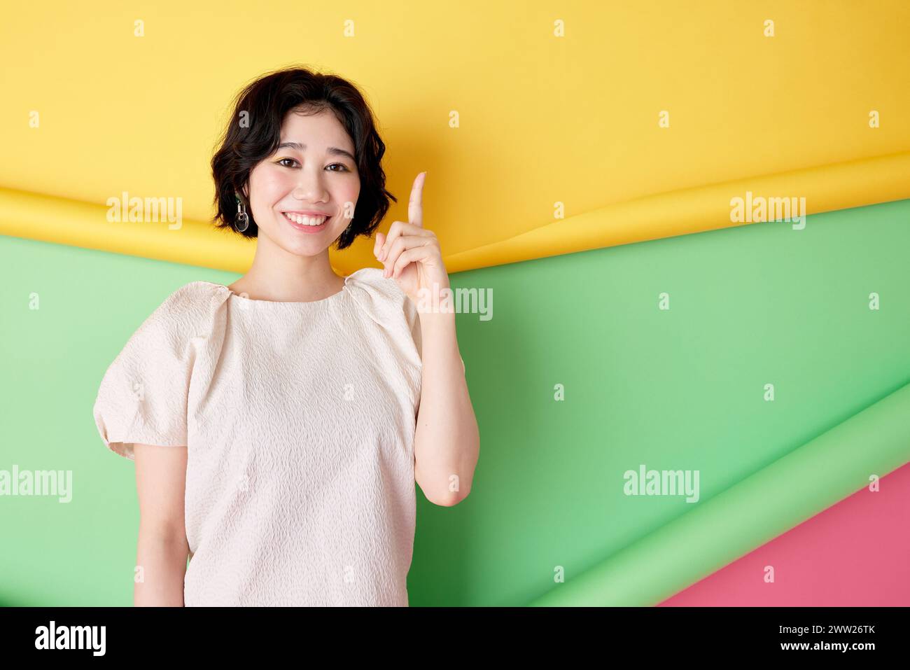 Donna asiatica che punta il dito contro il muro colorato Foto Stock