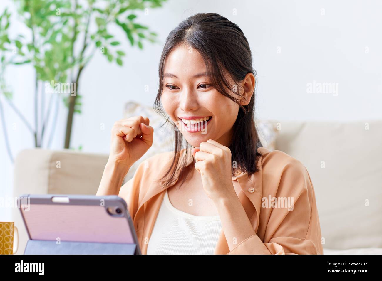 Donna asiatica sorridente mentre usa un tablet computer Foto Stock