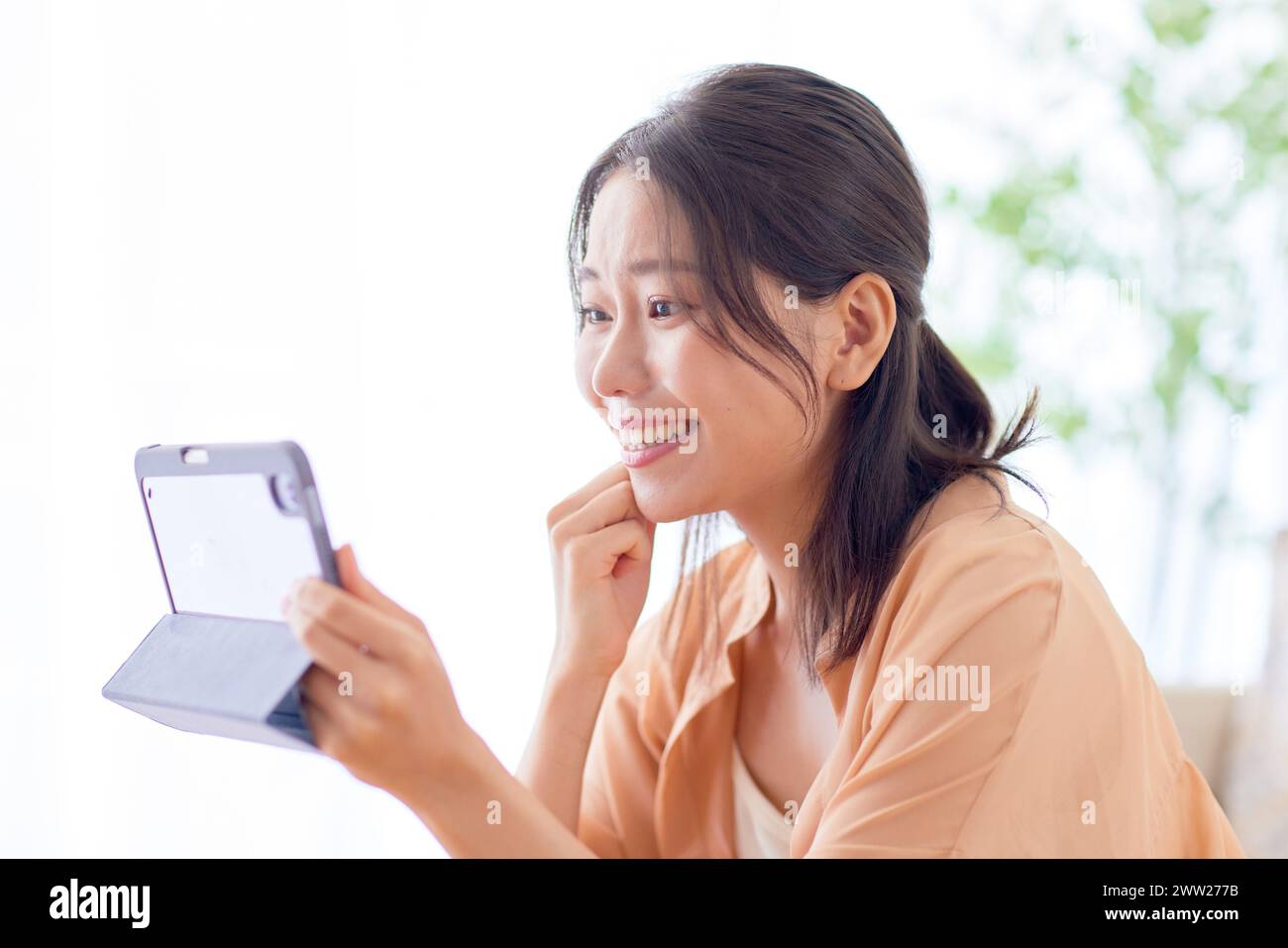 Una donna sorridente mentre tiene in mano un tablet Foto Stock