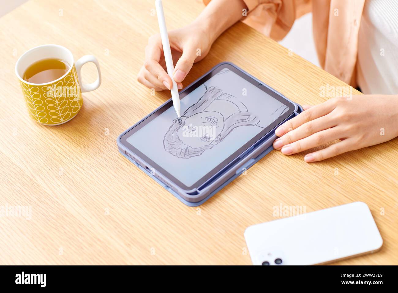 Una donna che disegna su un tablet con una penna Foto Stock