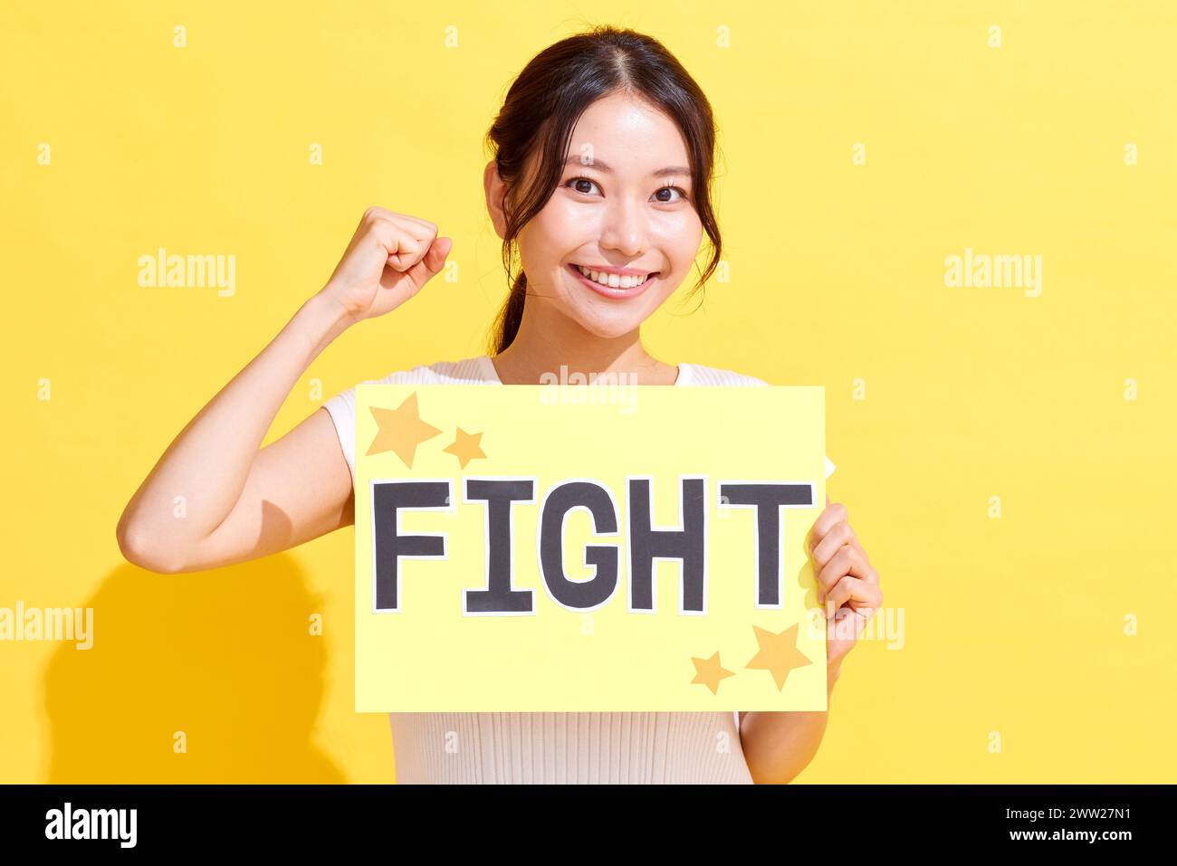 Donna asiatica con un cartello da combattimento su sfondo giallo Foto Stock