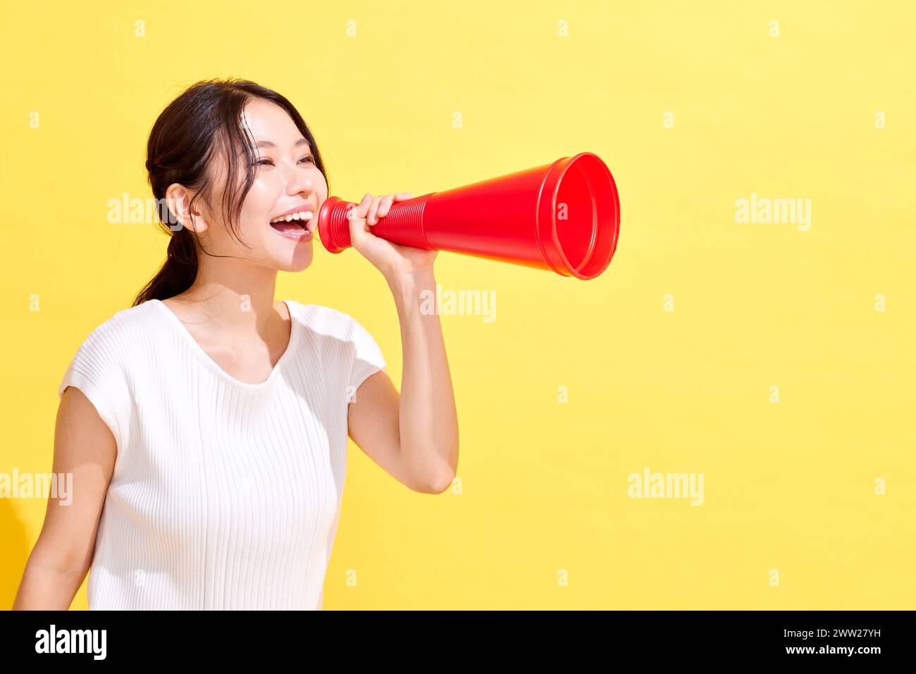 Donna asiatica che urla in un megafono Foto Stock