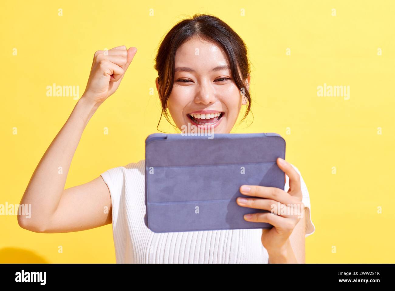 Donna asiatica che tiene un tablet e alza il pugno Foto Stock