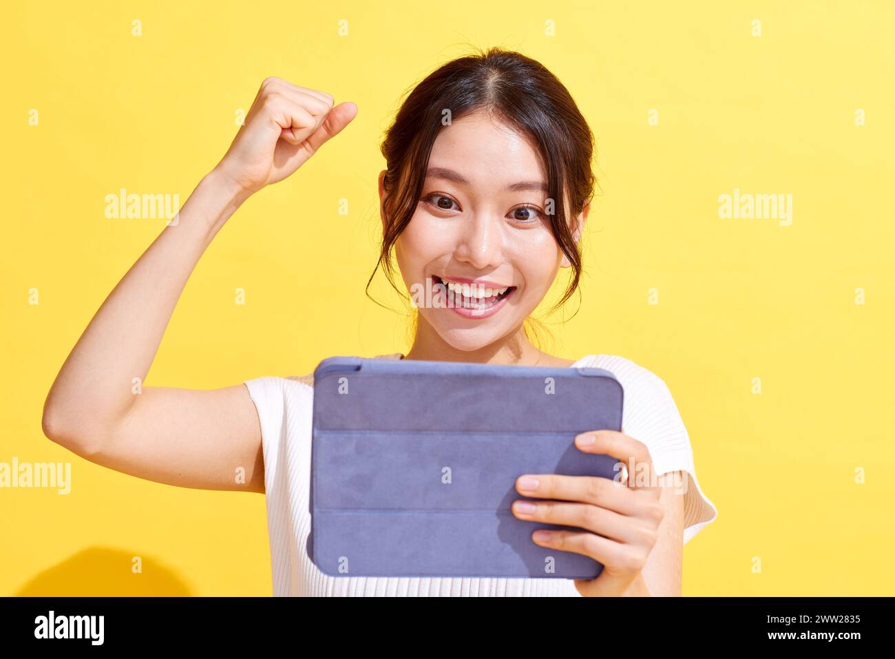 Donna asiatica che tiene un tablet computer e alza pugno Foto Stock