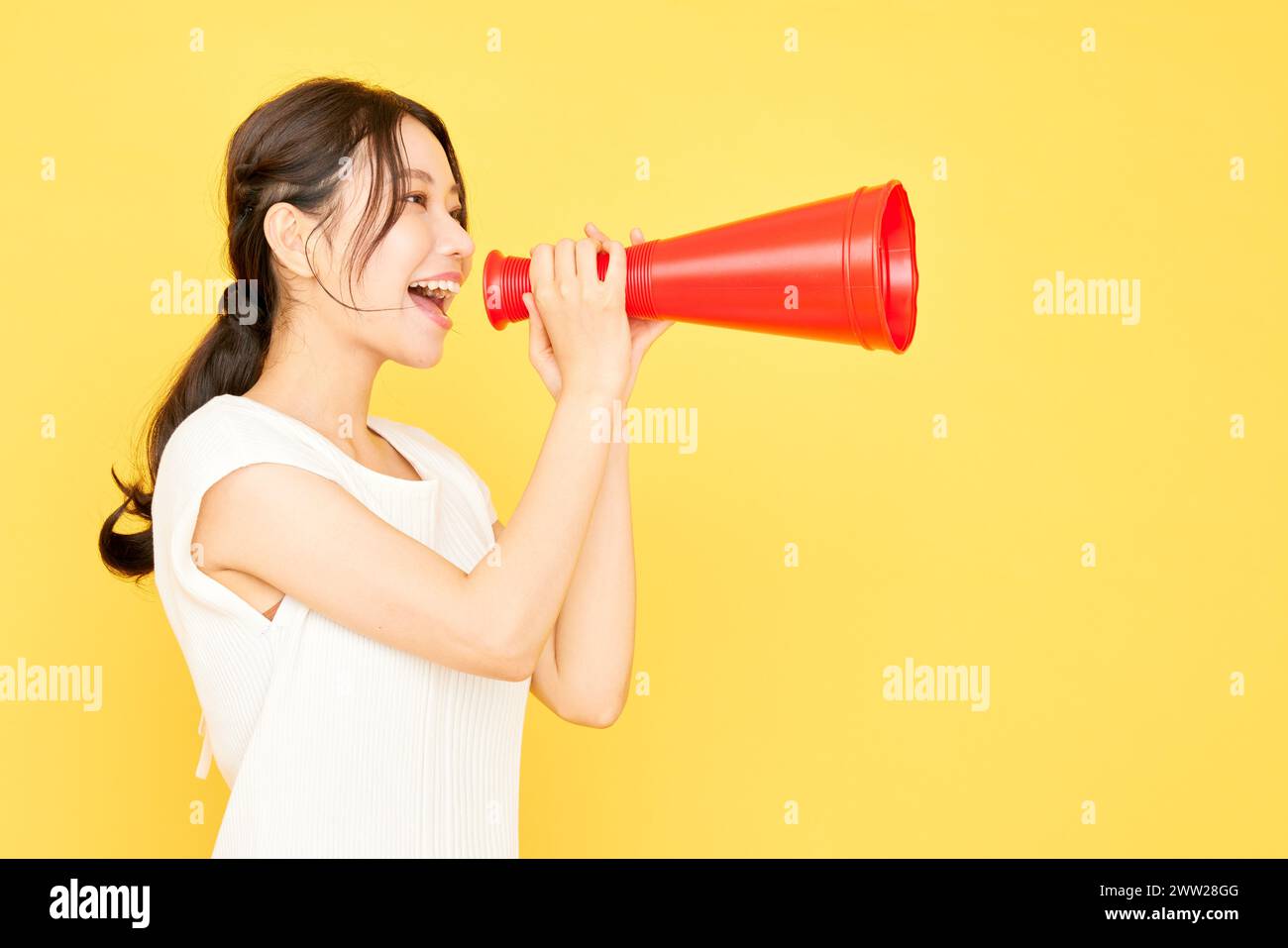 Donna asiatica che urla in un megafono rosso Foto Stock