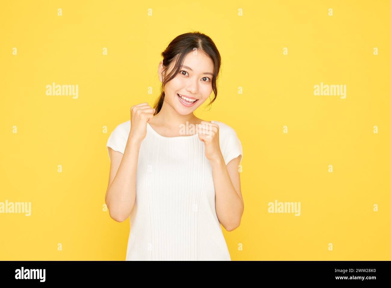 Una donna in abito bianco sorridente e con i pugni in mano Foto Stock