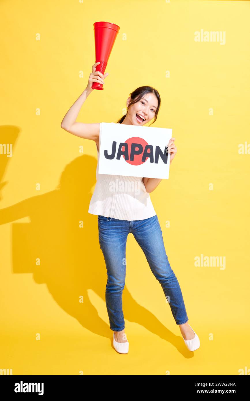 Donna giapponese con un cartello con testo giapponese e un megafono rosso Foto Stock