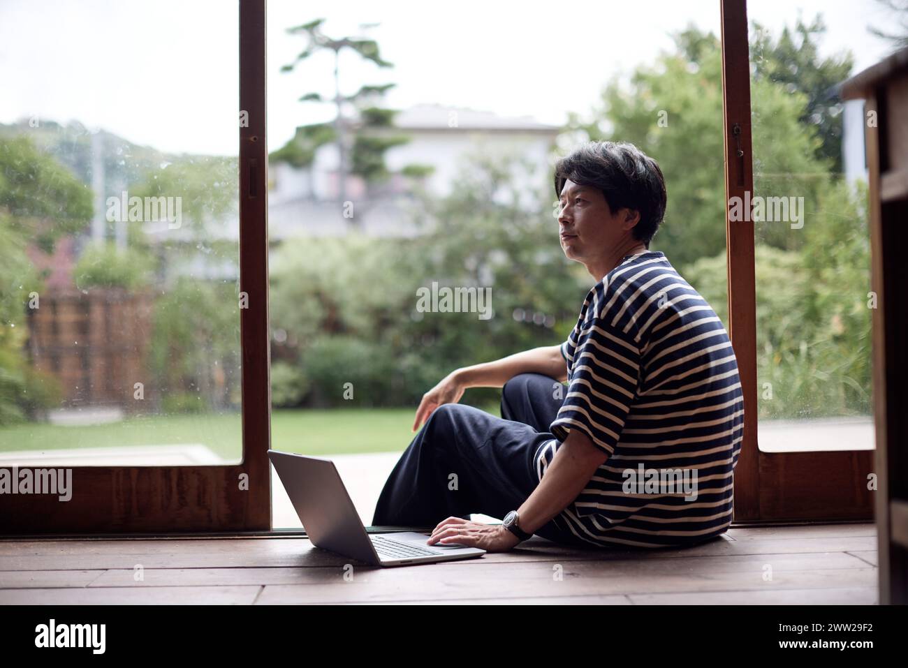 Un uomo seduto sul pavimento con un portatile Foto Stock