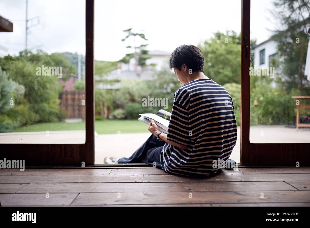 Un uomo seduto sul pavimento a leggere un libro Foto Stock