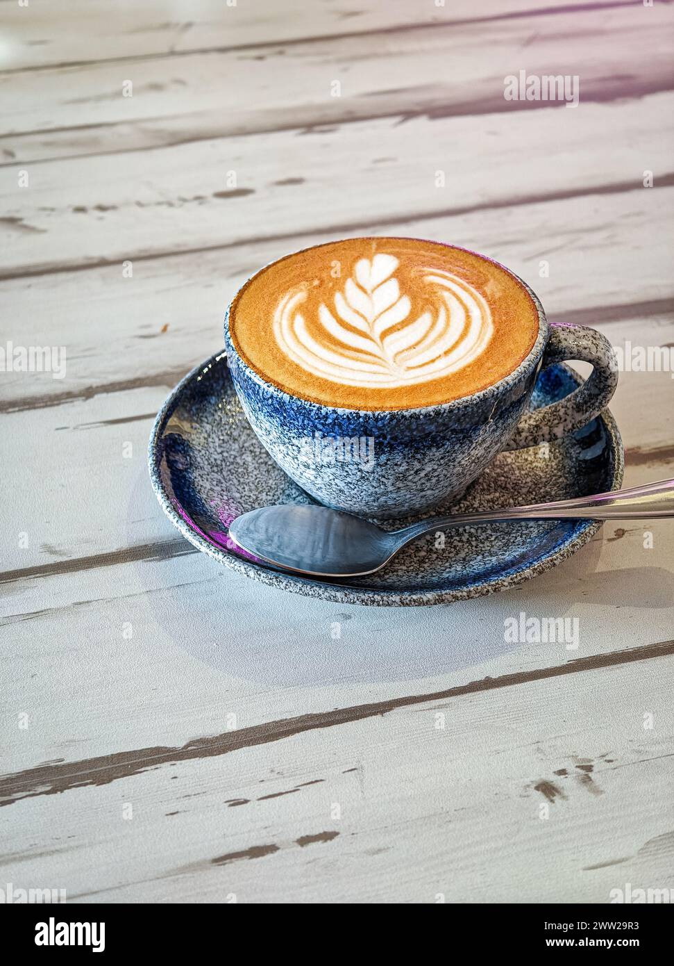 Caffè bianco piatto in una tazza blu sopra un tavolo di legno. Copia spazio. Foto Stock