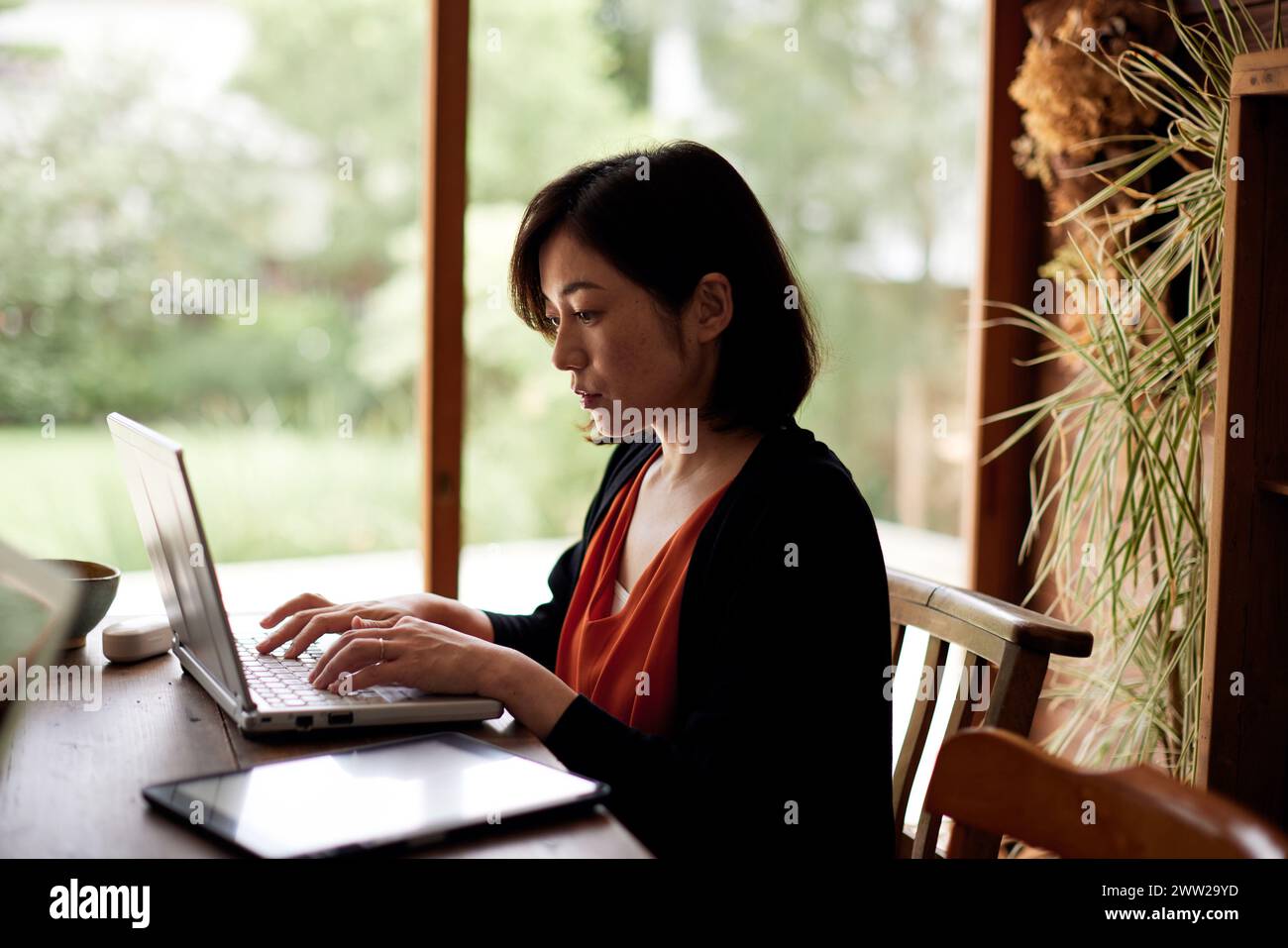 Una donna seduta a un tavolo con un computer portatile Foto Stock