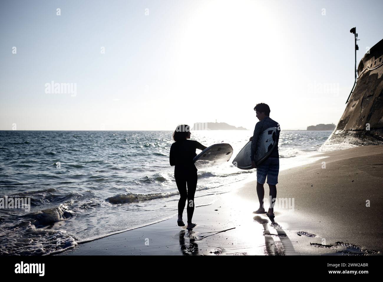 Un uomo e una donna in piedi sulla spiaggia che reggono tavole da surf Foto Stock