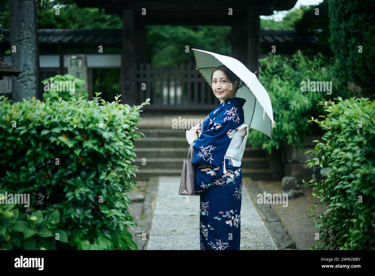 Una donna in kimono sotto un ombrello Foto Stock