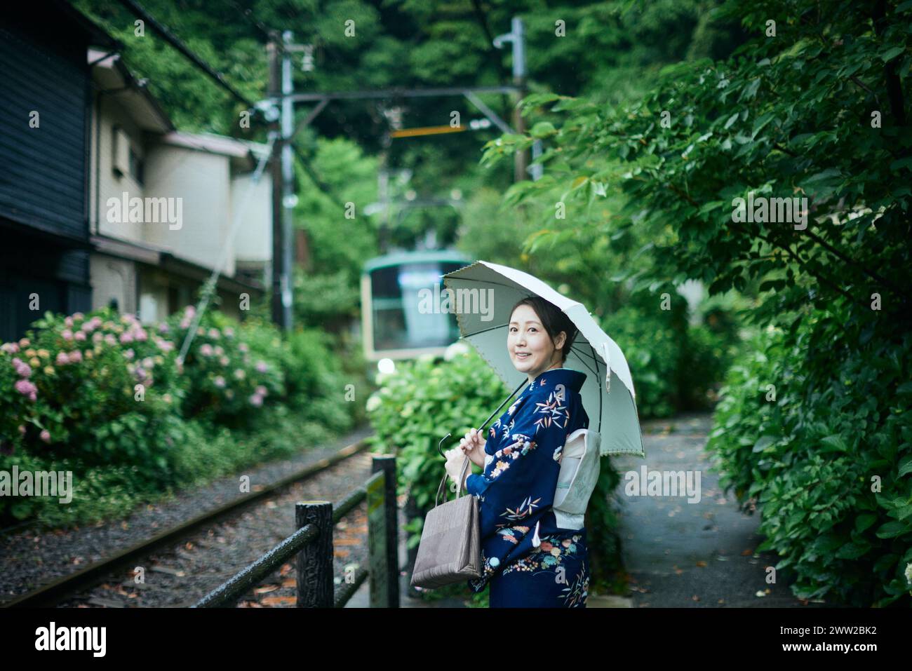 Una donna in kimono in piedi su un binario del treno Foto Stock