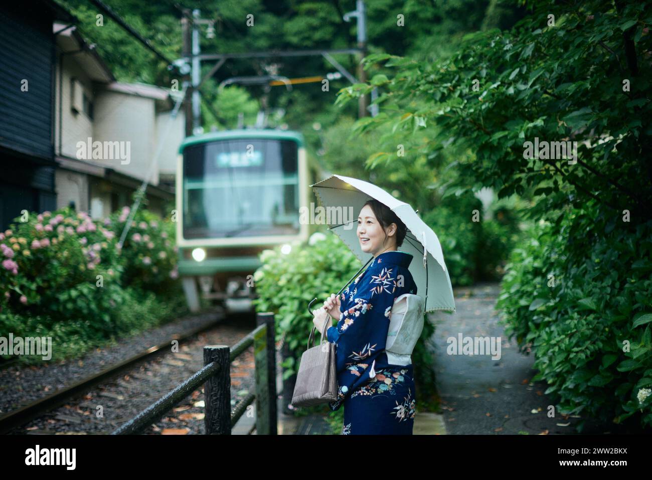 Una donna in kimono si trova su un binario del treno Foto Stock