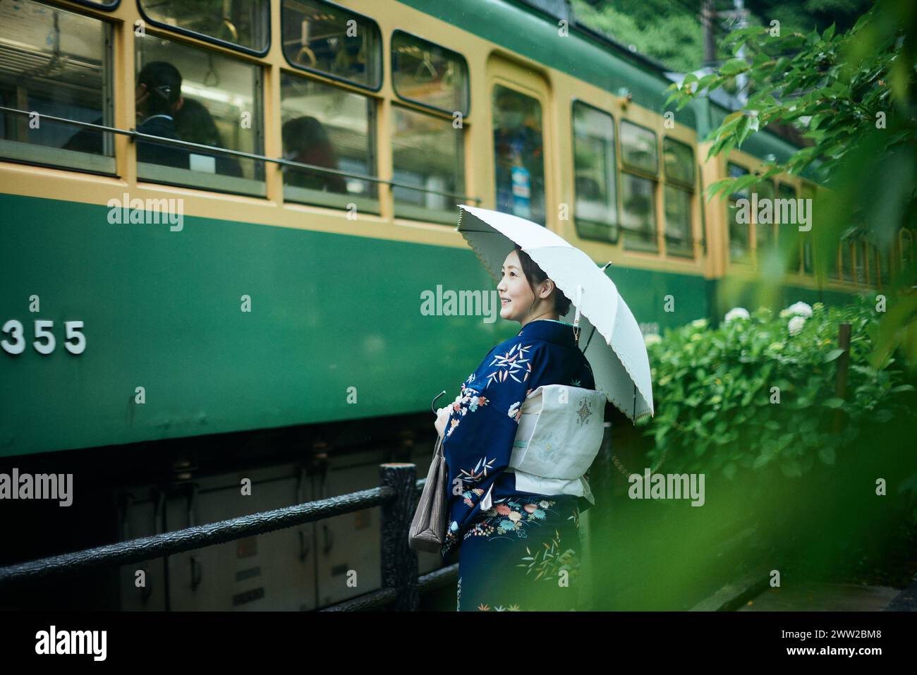 Una donna in kimono si trova accanto a un treno Foto Stock