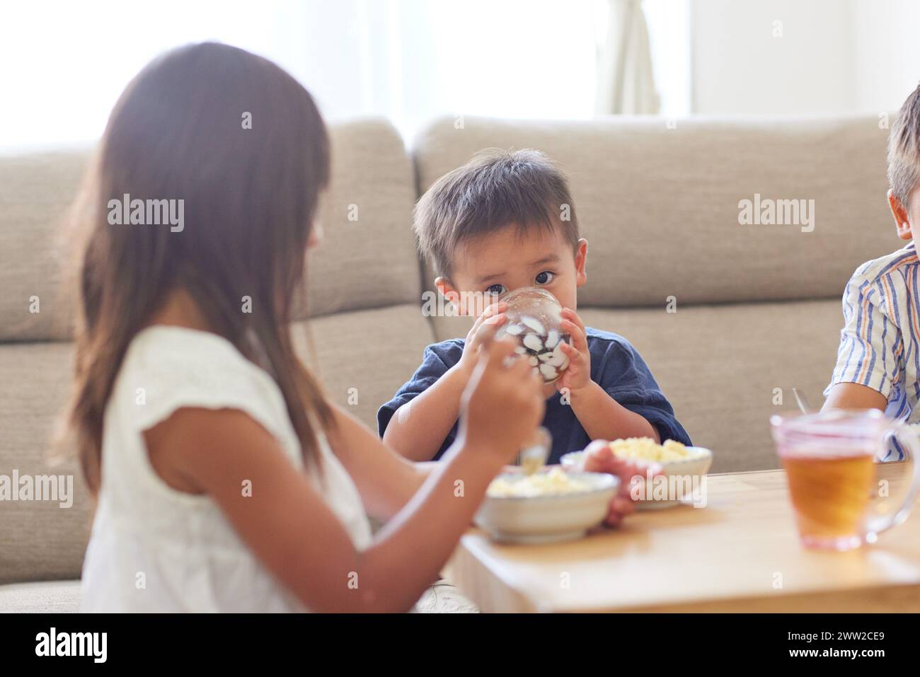 Bambini seduti a un tavolo a mangiare cibo Foto Stock