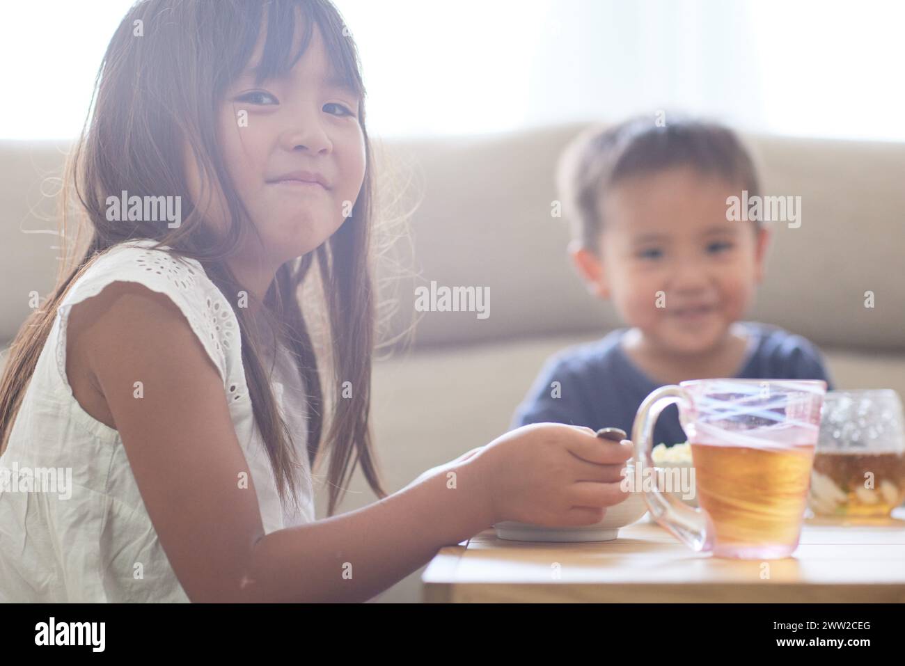 Bambini seduti a un tavolo a mangiare cibo Foto Stock