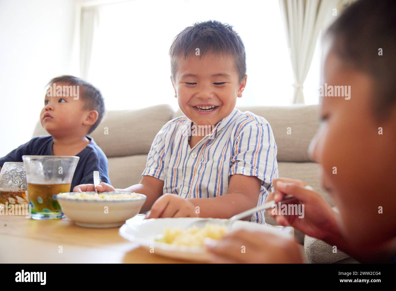 Bambini seduti a un tavolo a mangiare cibo Foto Stock
