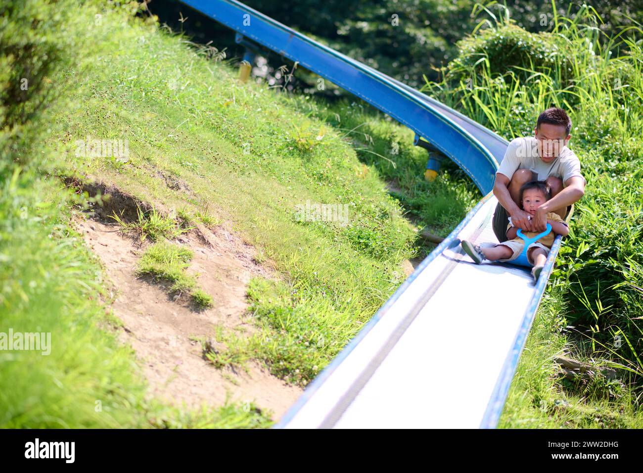 Un uomo e un bambino che cavalcano uno scivolo giù da una collina Foto Stock