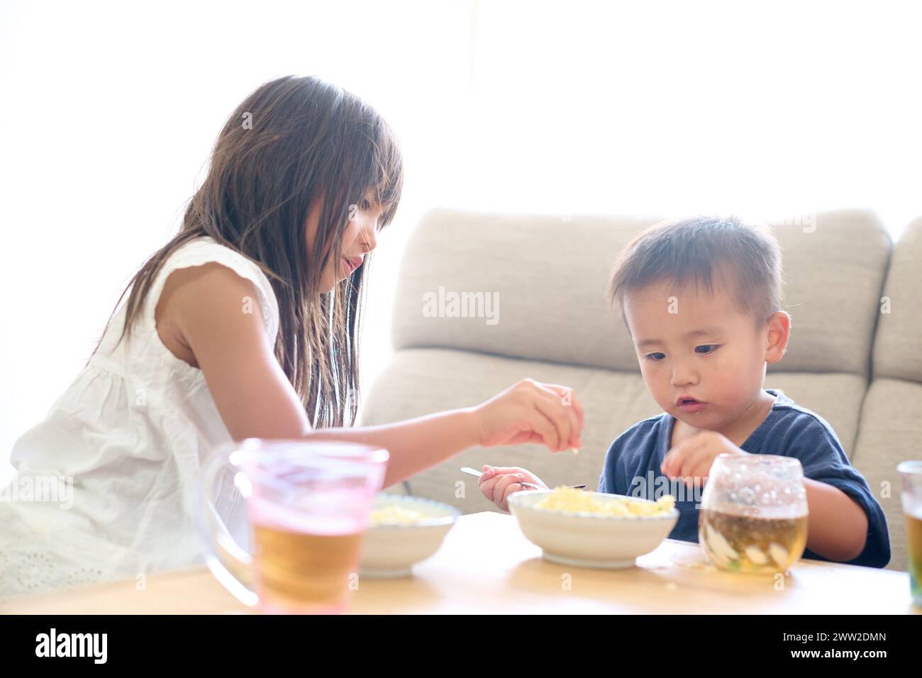 Bambini seduti a un tavolo a mangiare cibo Foto Stock