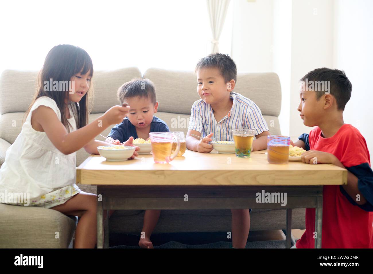 Bambini seduti a un tavolo a mangiare cibo Foto Stock