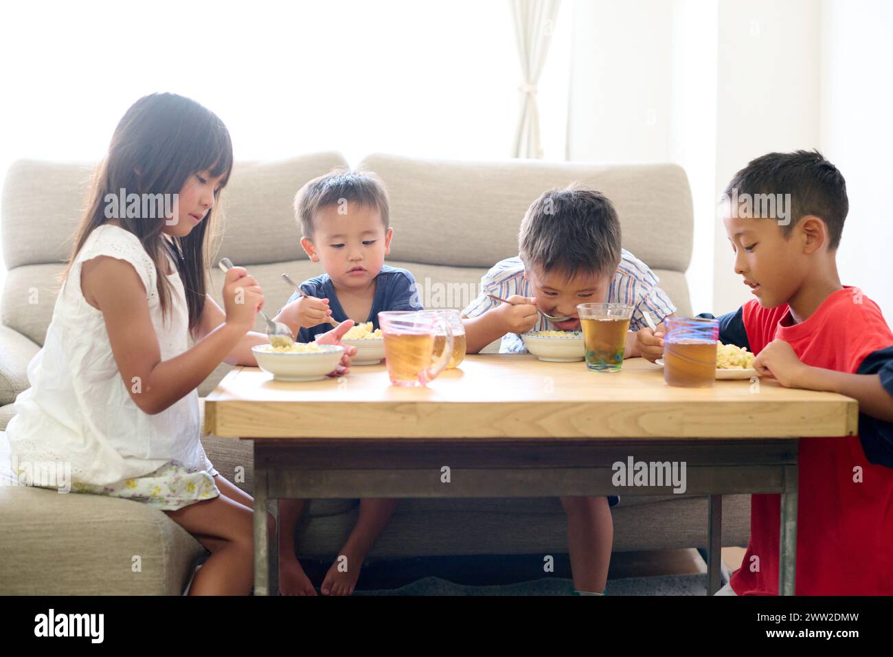 Bambini seduti a un tavolo a mangiare cibo Foto Stock
