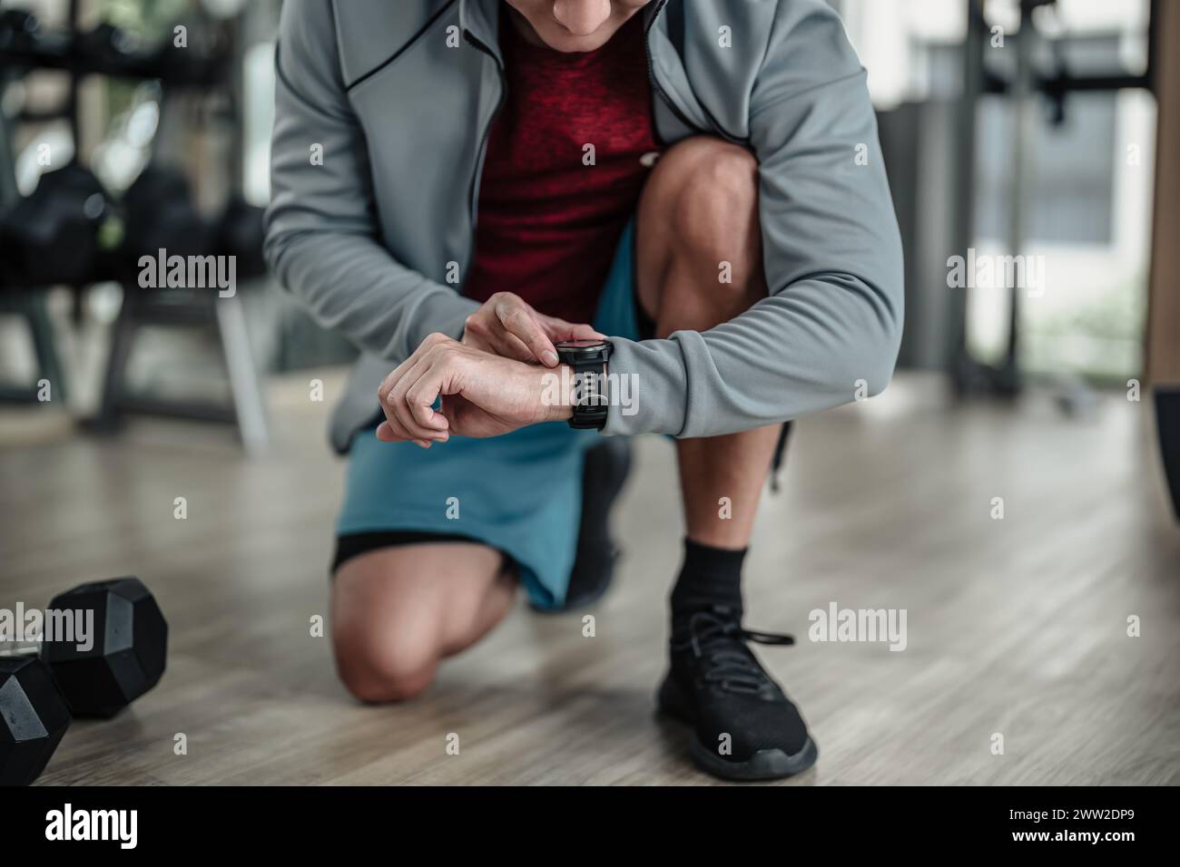 Un uomo che controlla lo smartwatch durante gli allenamenti in palestra. Fitness, allenamento e formazione al concetto. Foto Stock