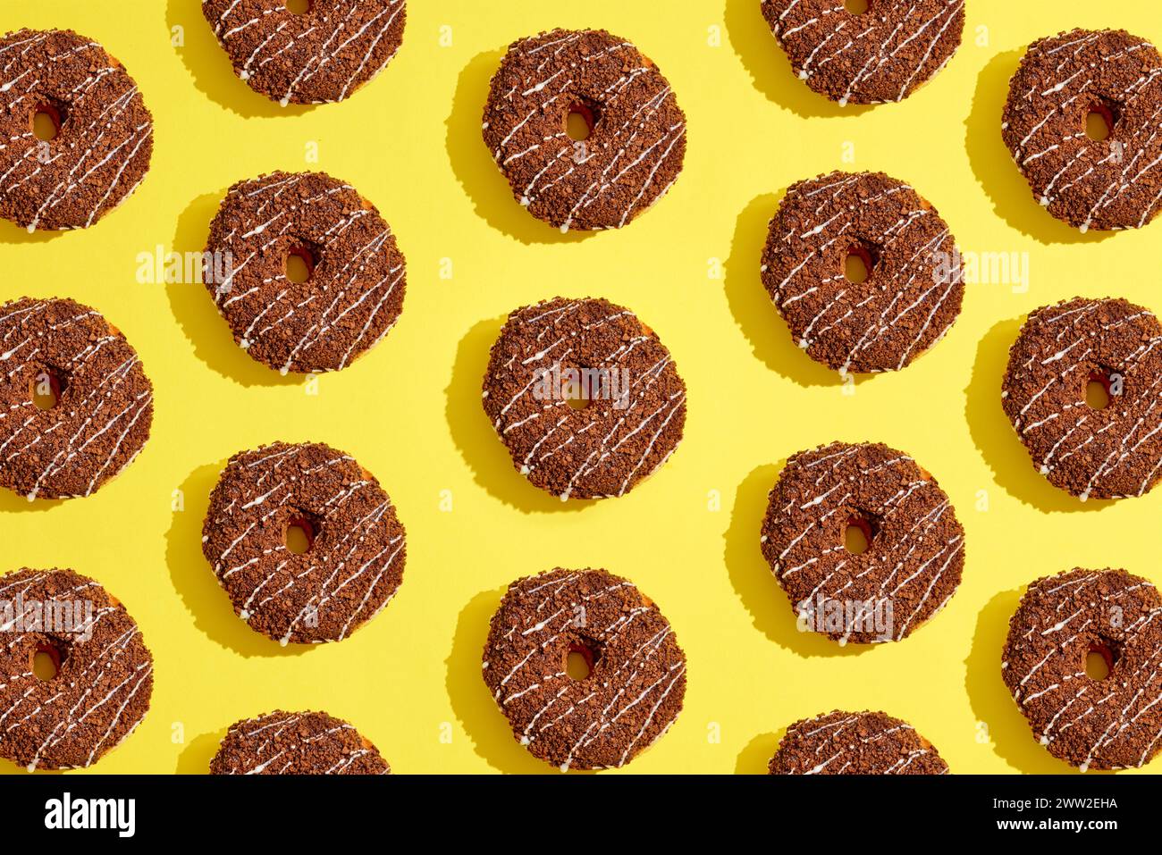 Un motivo di ciambelle al cioccolato su sfondo giallo Foto Stock